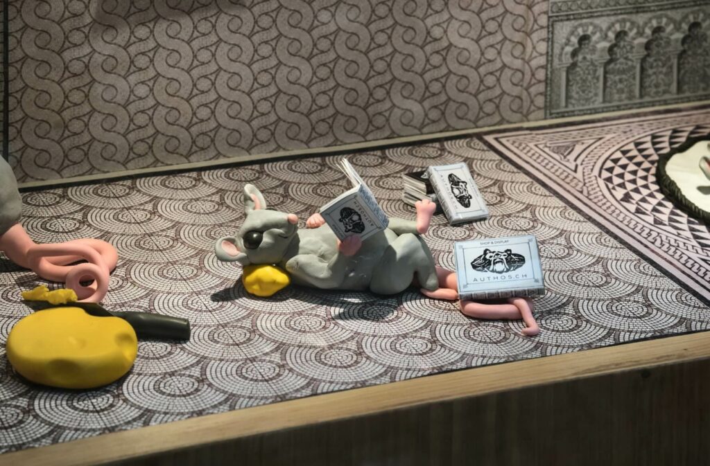 a mouse is reading the AUTHOS book in a shop display